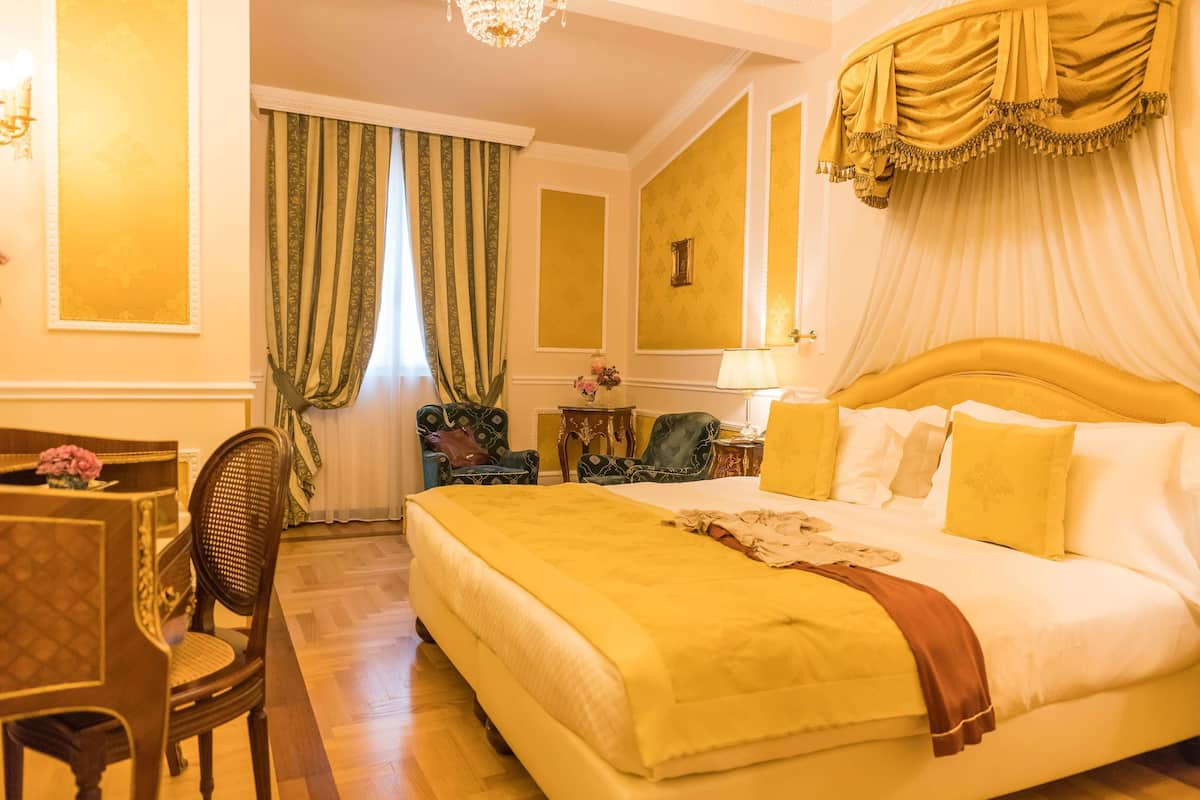 Ein Hotelzimmer mit einem großen Bett, einer Sitzecke mit Tisch und Stühlen sowie einem Kronleuchter.