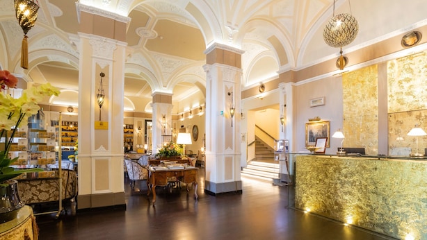 A lobby with ornate columns, a reception desk, and a staircase.