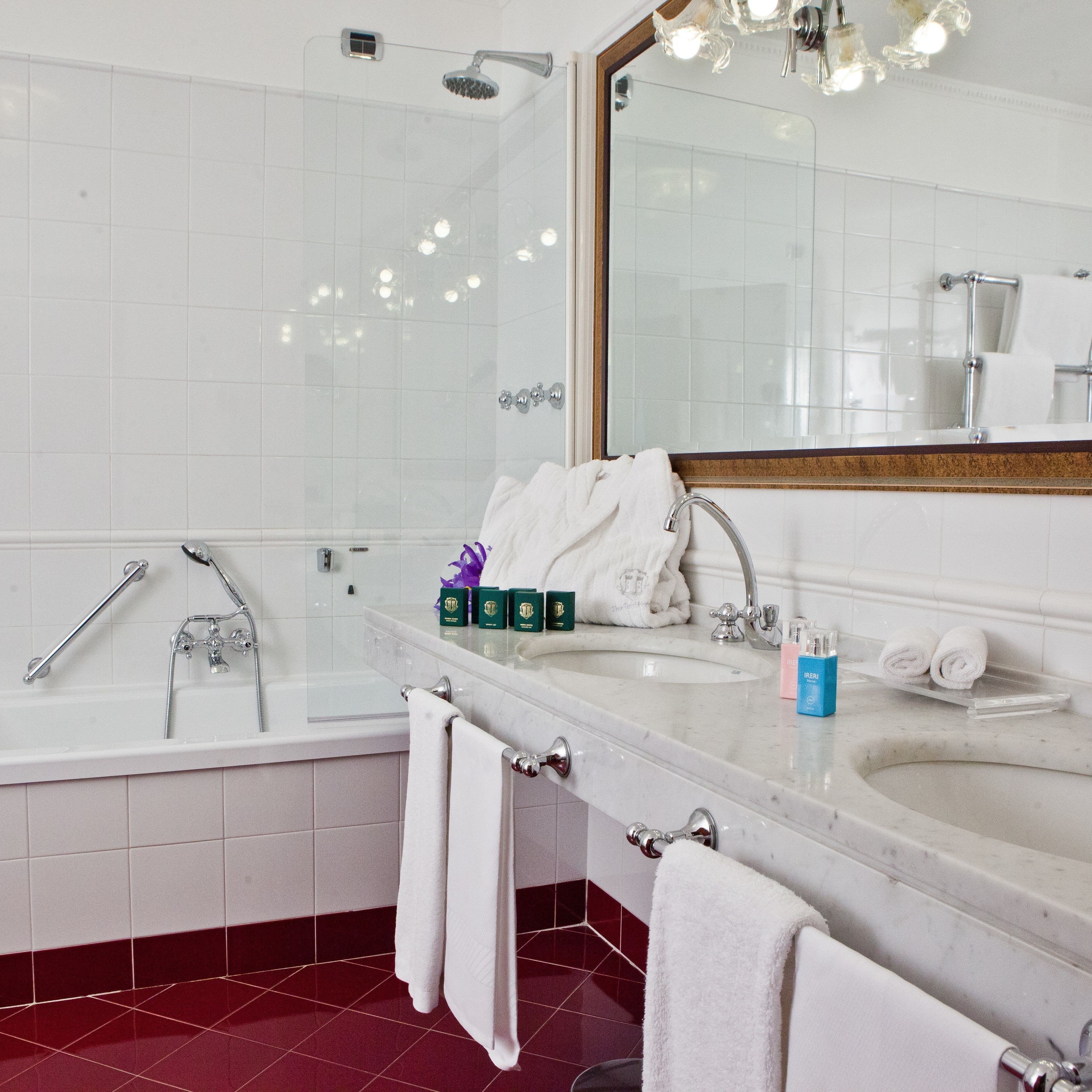Un baño moderno con una bañera, un lavabo y un espejo grande.