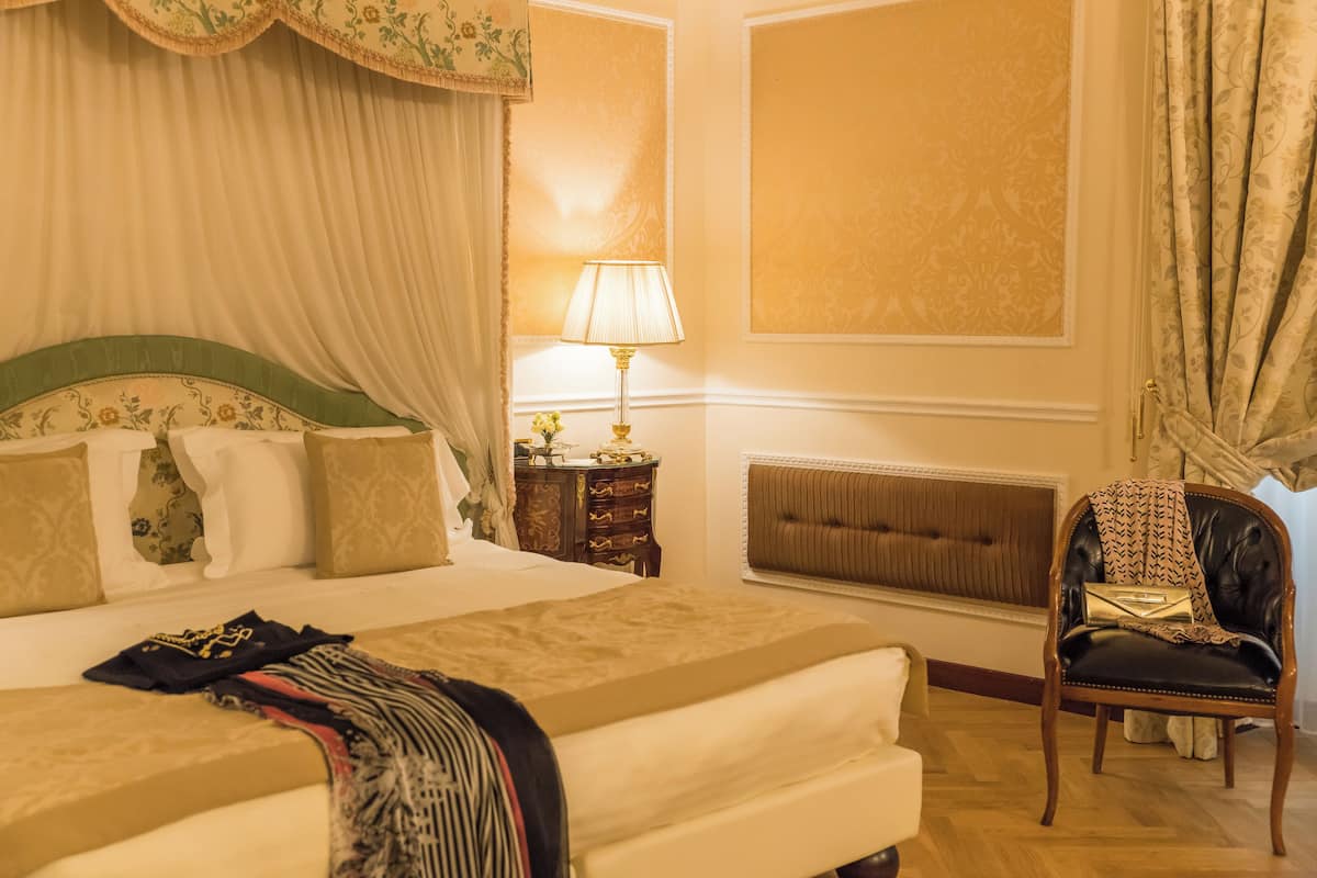 Ein Hotelzimmer mit einem großen Bett, einem Sessel, einem Nachttisch und einer Lampe.