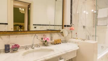 A bathroom with a marble sink, a large mirror, a shower, and a chandelier.