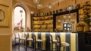 A bar area with a striped counter, bar stools, and hanging spherical light fixtures.
