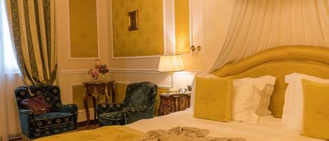 A hotel room with a large bed, two armchairs, a nightstand, and a lamp.