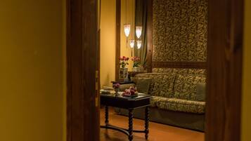 Una stanza accogliente con divano decorato, un tavolino con un vaso di fiori e un pannello ornamentale al muro.