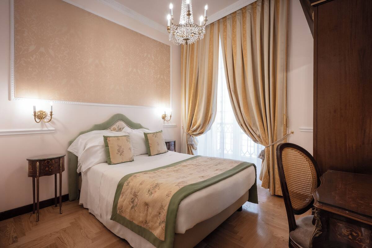 Ein Schlafzimmer mit einem großen Bett, Holzboden, einer Chandelieber und einem Sessel.