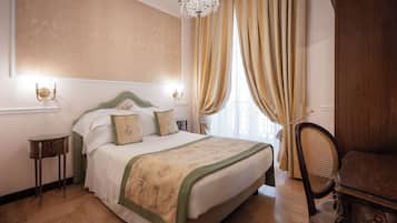 A bedroom with a large bed, a wooden floor, a chandelier, and a chair.