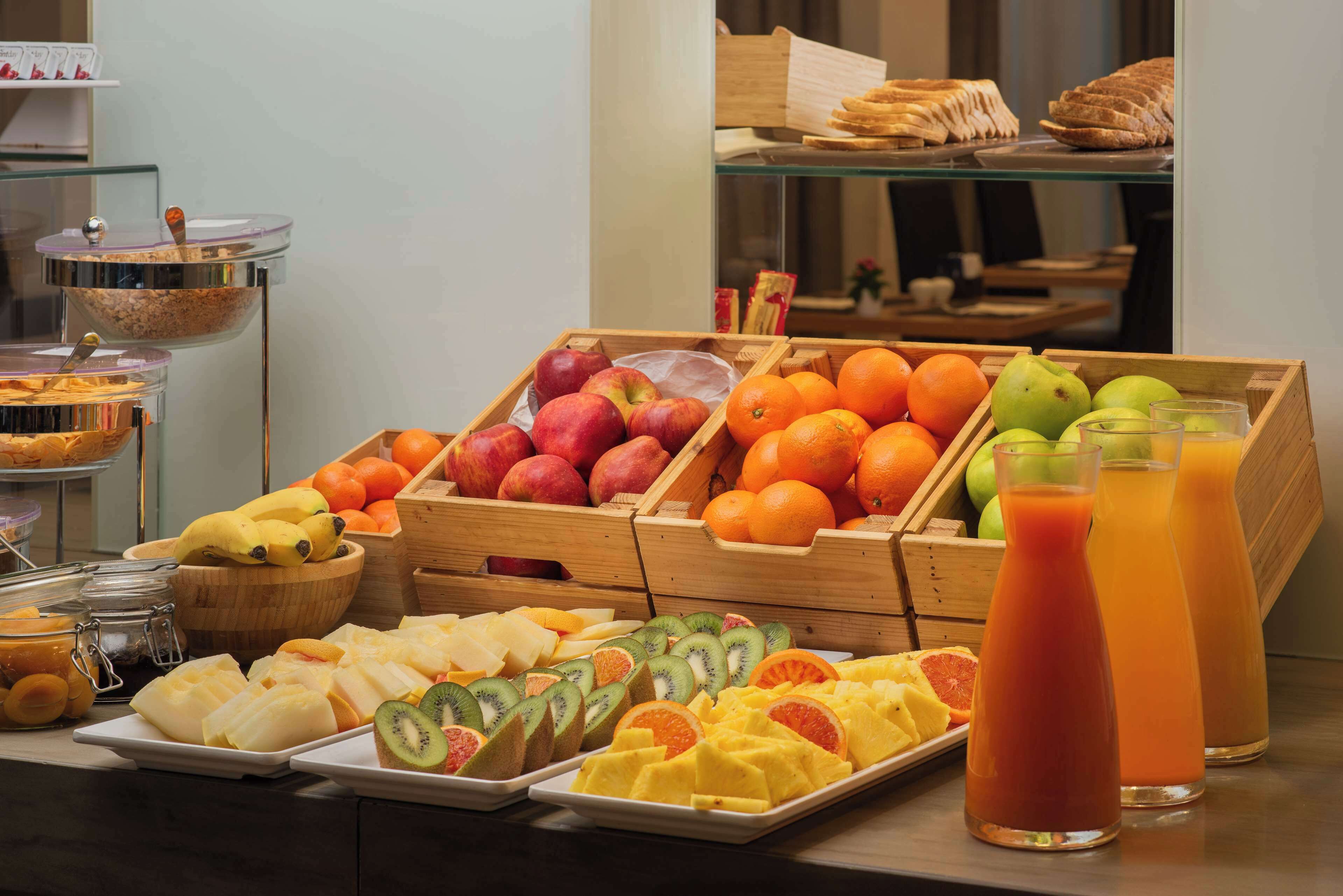 Un bufé de desayuno con diversas frutas, jugos y pastelería.