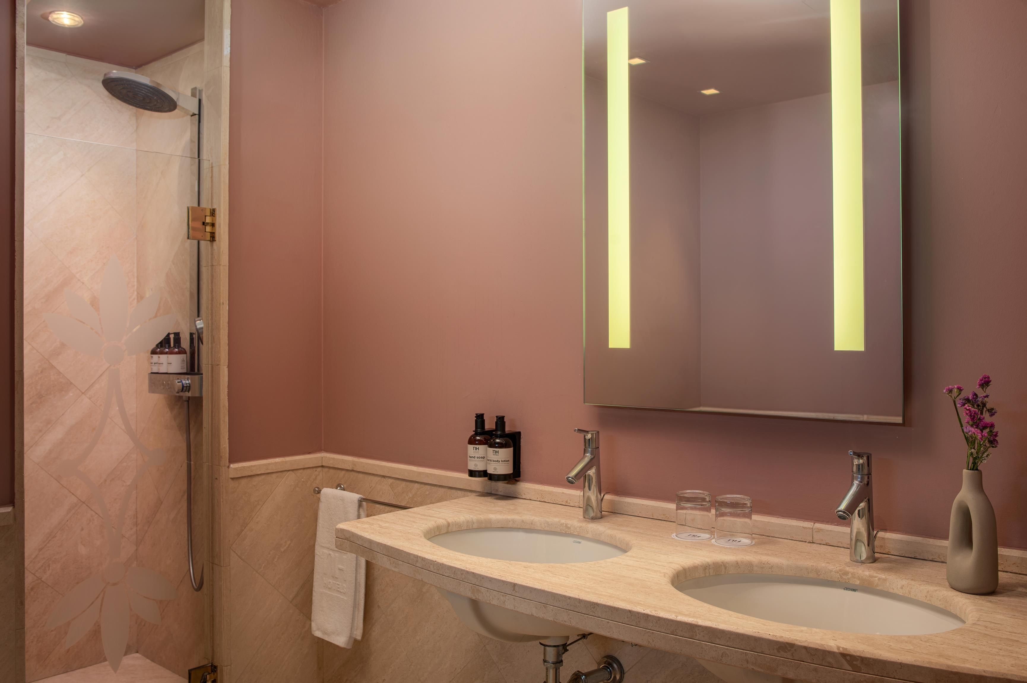 Une salle de bain avec deux lavabos, une douche et un miroir.