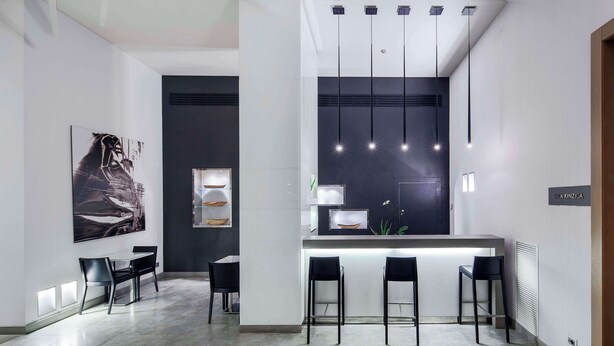 A modern kitchen with a central island, bar stools, pendant lighting, and a large framed artwork on the wall.