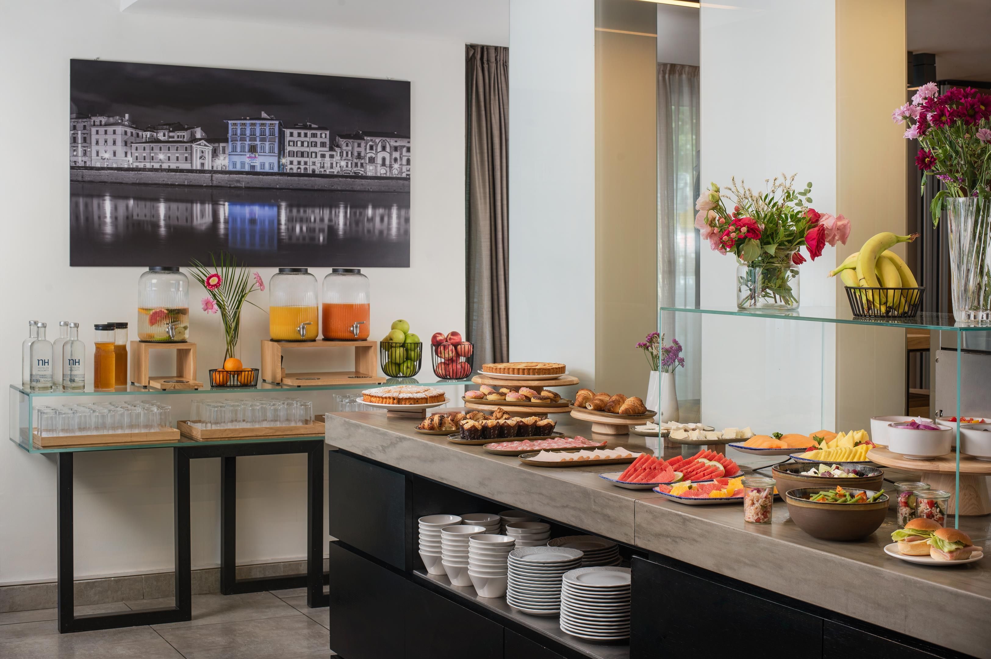A buffet setup with various food items, a glass display case with bottles, and a wall-mounted painting.