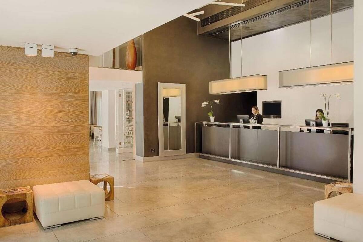 Een moderne hotel lobby met een receptiebalie, een zithoek en een grote spiegel.