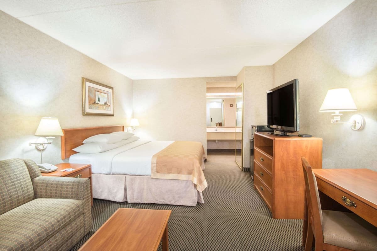 A hotel room with a bed, a TV, a desk, a chair, and a couch.