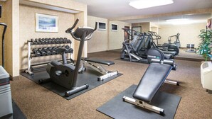 A gym with exercise equipment including dumbbells, treadmills, and a bench. - Travelodge by Wyndham Pueblo (Pueblo)