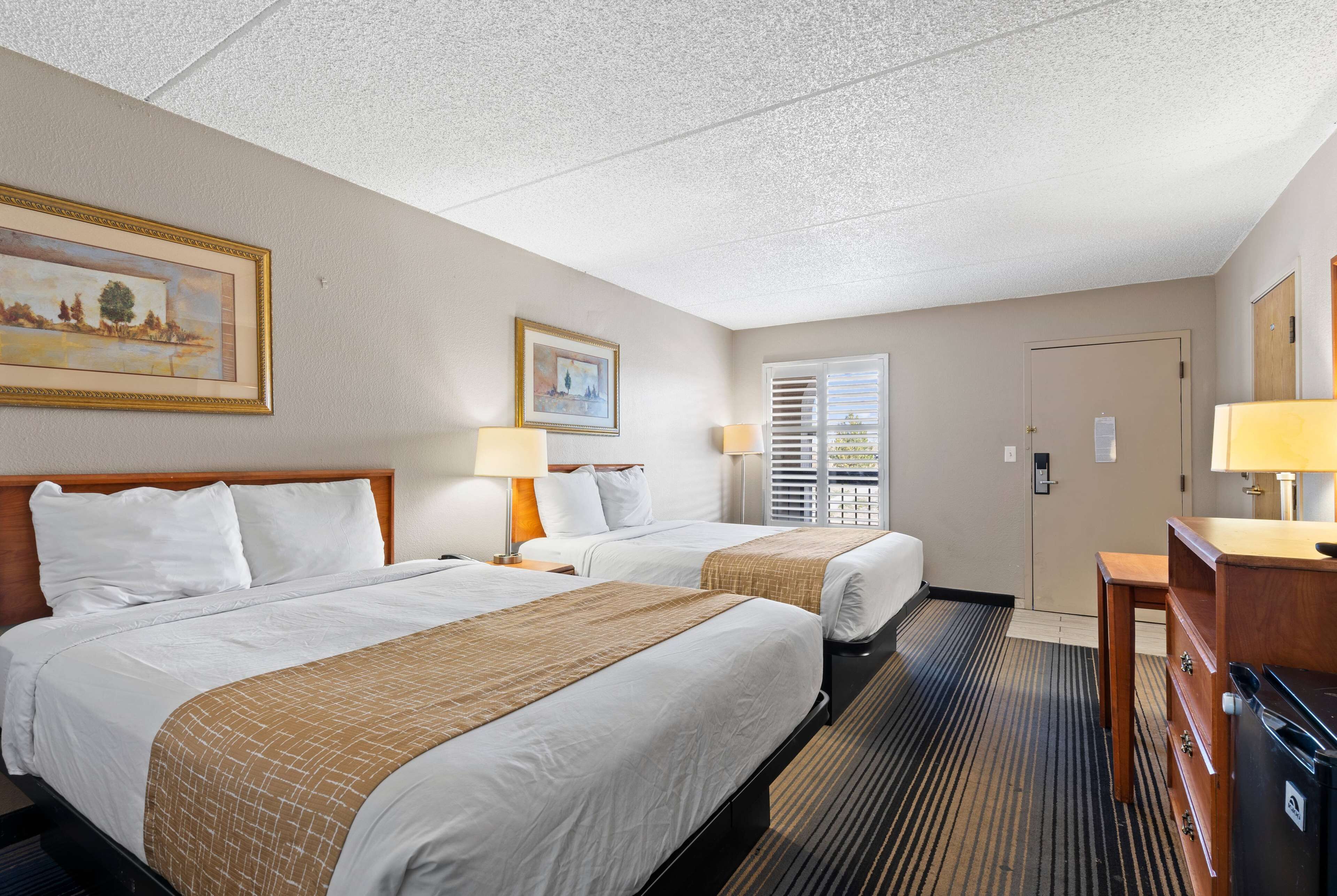 A hotel room with two beds, a desk, and a dresser.