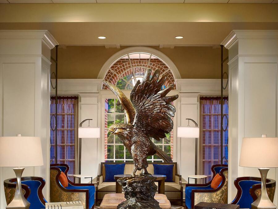 Eine Lobby mit einer zentralen Statue, einer Sitzecke und einer Decke mit einer einzigartigen Leuchte.