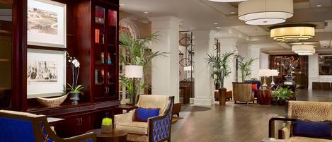 A spacious lobby with a wooden reception desk, framed photographs, and comfortable seating areas.