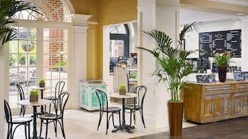 A cafe with tables and chairs, a coffee machine, and a menu board.