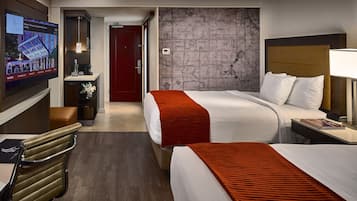 A hotel room with two beds, a TV, a desk, and a map on the wall.