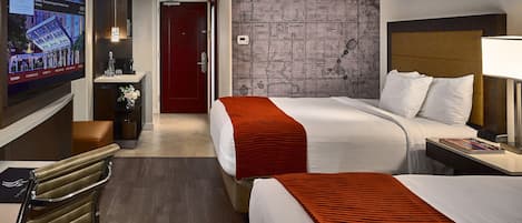 A hotel room with two beds, a TV, a desk, and a map on the wall.