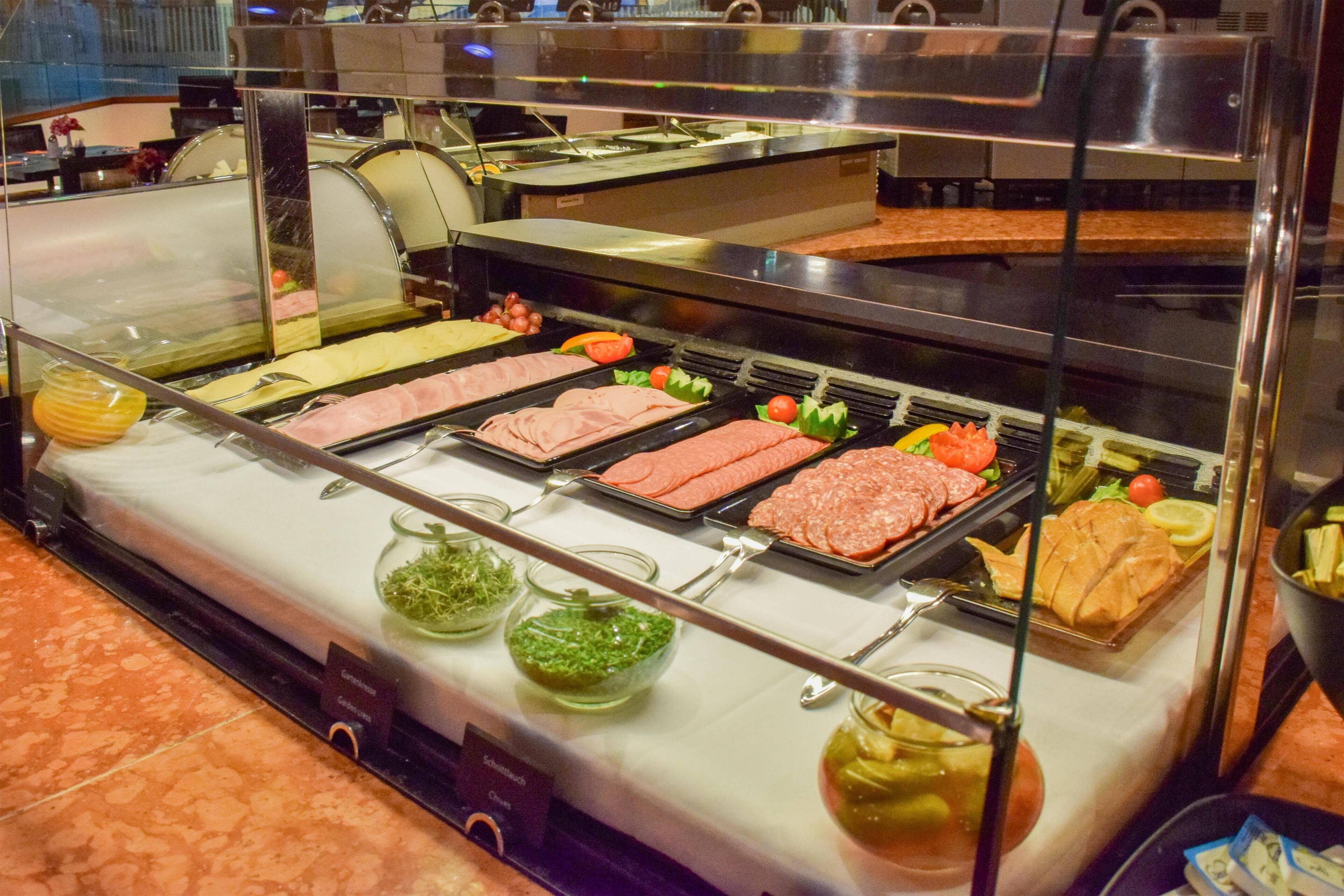 A buffet with various meats, vegetables, and condiments.