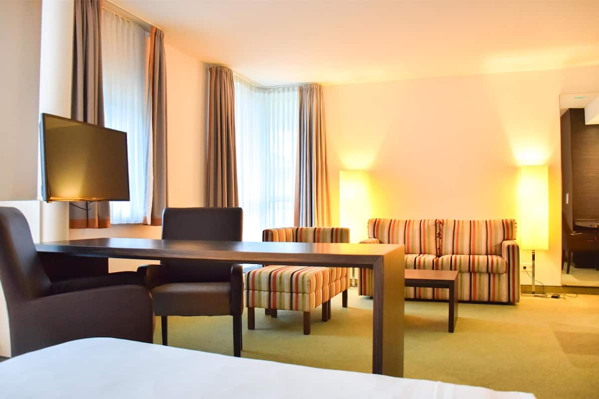 Una habitación de hotel con una cama, un escritorio con una silla, un sofá y un televisor.