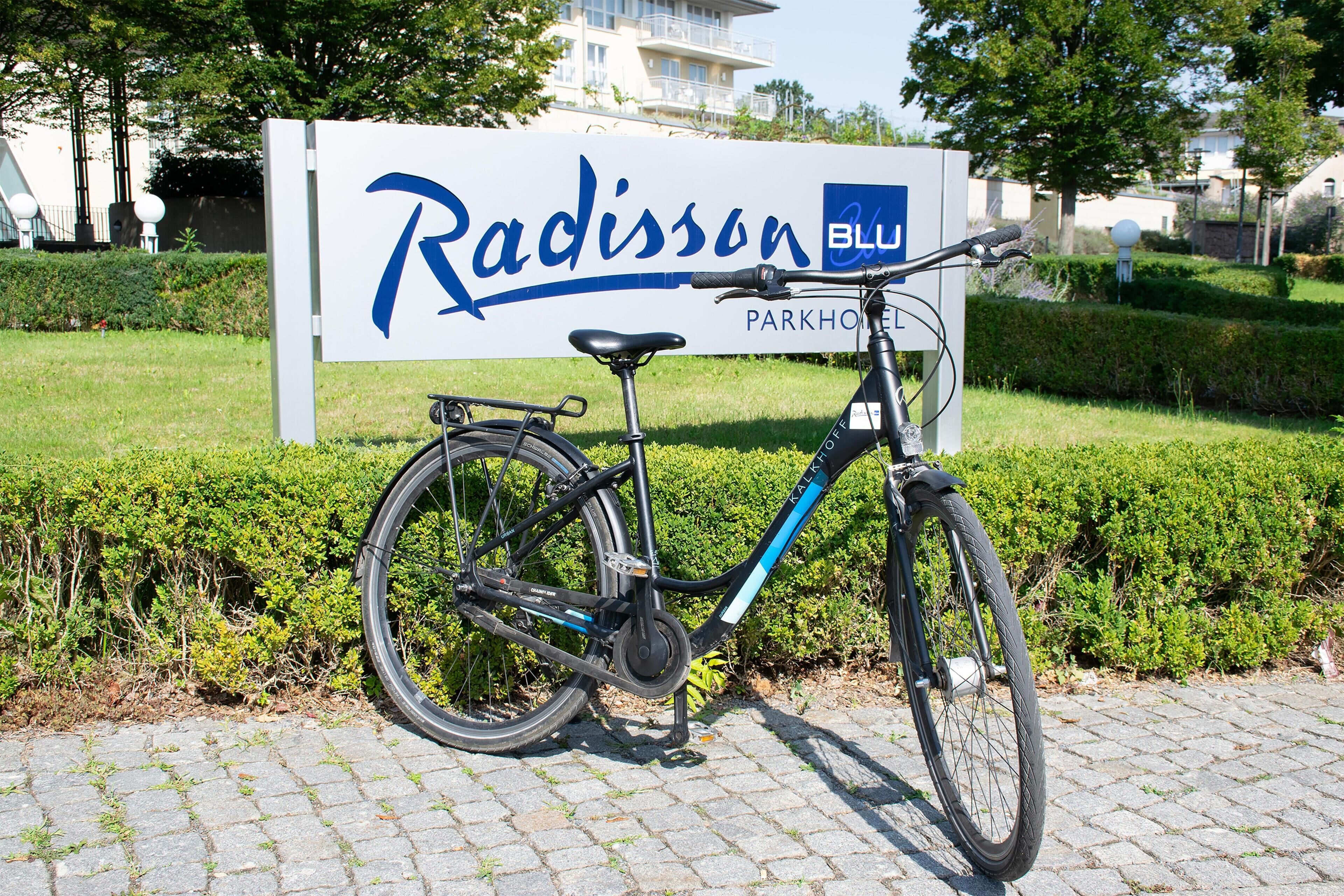 A bicycle parked in front of a sign for Radisson Blu Parkhotel.