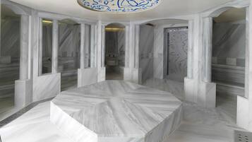 Un baño moderno con suelo de mármol, un lavamanos central y un techo con caligrafía azul decorativa.