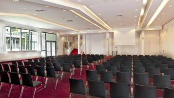 A conference room with rows of chairs, a red carpet, and a staircase leading to an upper level.