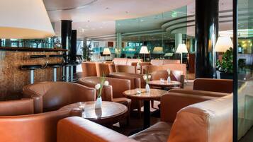 A modern hotel lobby with leather seating, round tables, and ambient lighting.