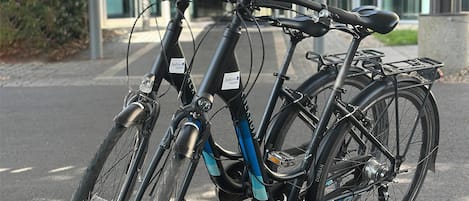 Ein Fahrrad steht unter einer Überdachung, im Hintergrund ein modernes Gebäude.