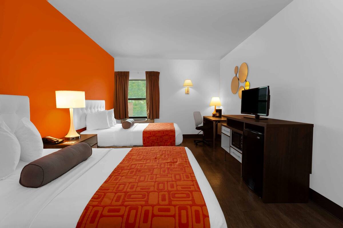 Habitación de hotel con dos camas, un escritorio, televisor y comedor.
