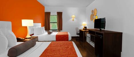 A hotel room with two beds, a desk, a television, and a dining area.