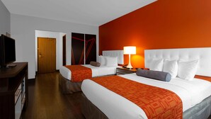 Habitación de hotel con dos camas, un televisor y una puerta que da a otra habitación.