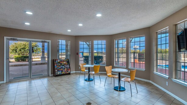 A spacious indoor area with large windows, a tiled floor, and several tables and chairs.
