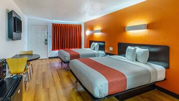 Une chambre d’hôtel avec deux lits, une télévision, un bureau et un coin repas.