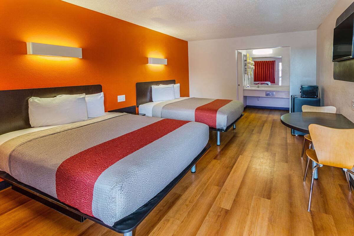 Une chambre d’hôtel avec deux lits, une table à manger et un téléviseur.