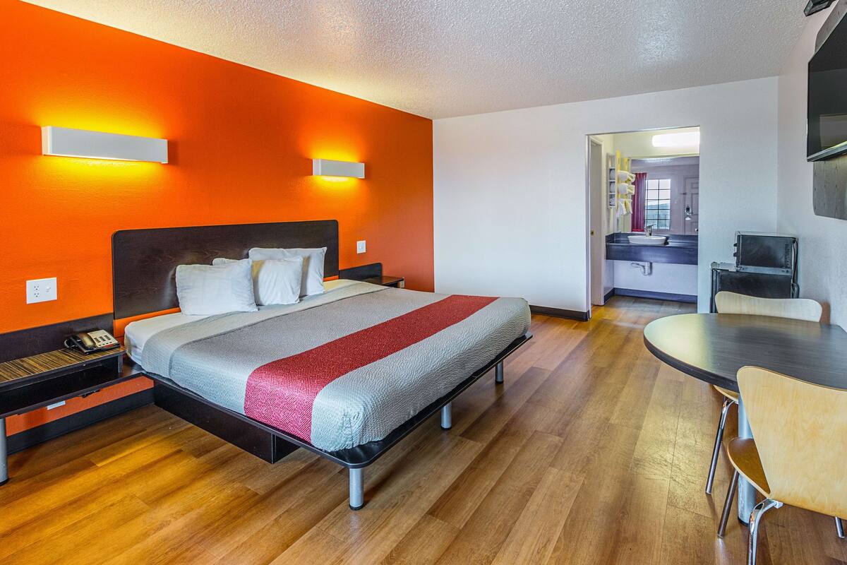 Une chambre d’hôtel avec un lit, une table de chevet et un bureau avec une chaise.