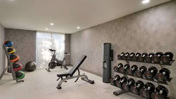 A gym with exercise equipment, including a bench, dumbbells, and a stationary bike.