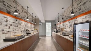 A modern kitchen with wooden cabinets, a central island, and pendant lighting. - La Quinta Inn & Suites by Wyndham Springfield (Springfield)