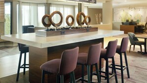 Eine moderne Bar mit einer zentralen Barinsel, Barhocker und einer dekorativen Holzskulptur.