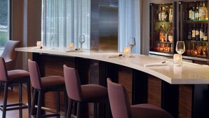 Eine Bar mit einer langen Theke, Barhocker und am jeweiligen Ende ein Weinglas.