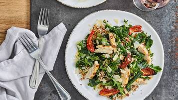 A plate of food with a fork and a glass of red wine on a table.
