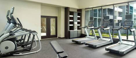 A gym with treadmills, a bench press, and exercise balls.