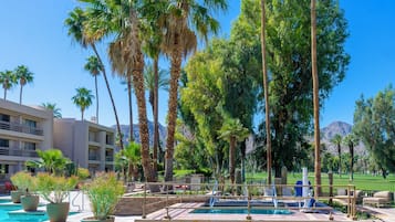 A pool area with palm trees, a pool, and a mountain in the background.