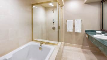 A modern bathroom with a glass-enclosed shower, a large bathtub, and a vanity with a sink and mirror.
