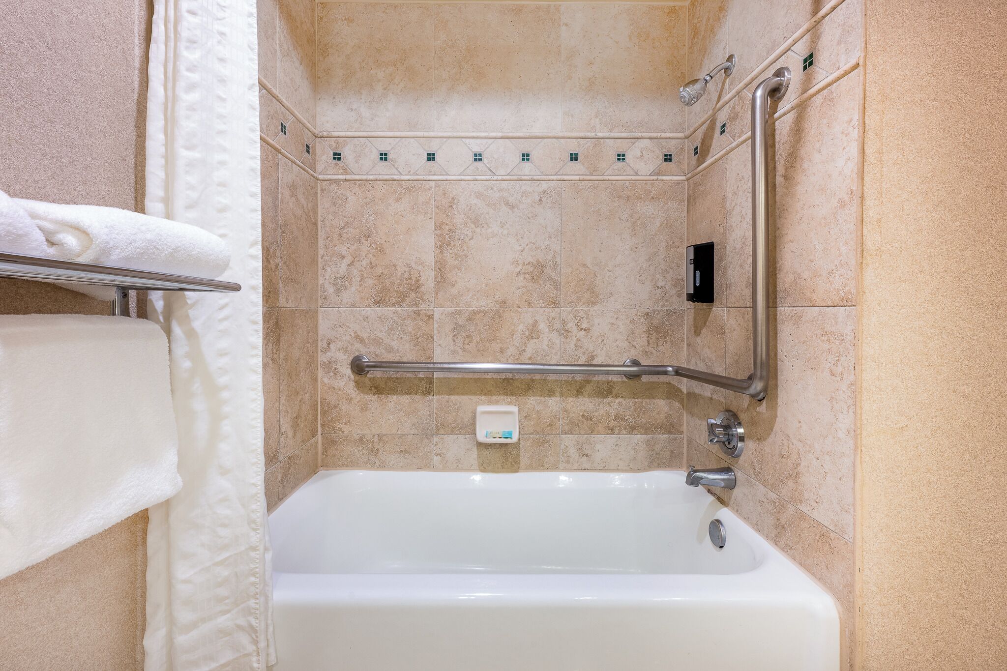 Un baño con bañera, barandilla y un perchero para toallas.