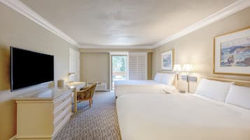 A hotel room with two beds, a desk with a flat-screen TV, a chair, and a window with blinds.