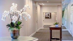 A hallway with a white orchid vase, a framed picture on the wall, and a small table with a plant. - Indian Wells Resort Hotel (Indian Wells)