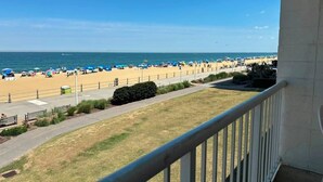 A beach view with a paved walkway, umbrellas, and a clear sky. - Ocean 27 (Virginia Beach)