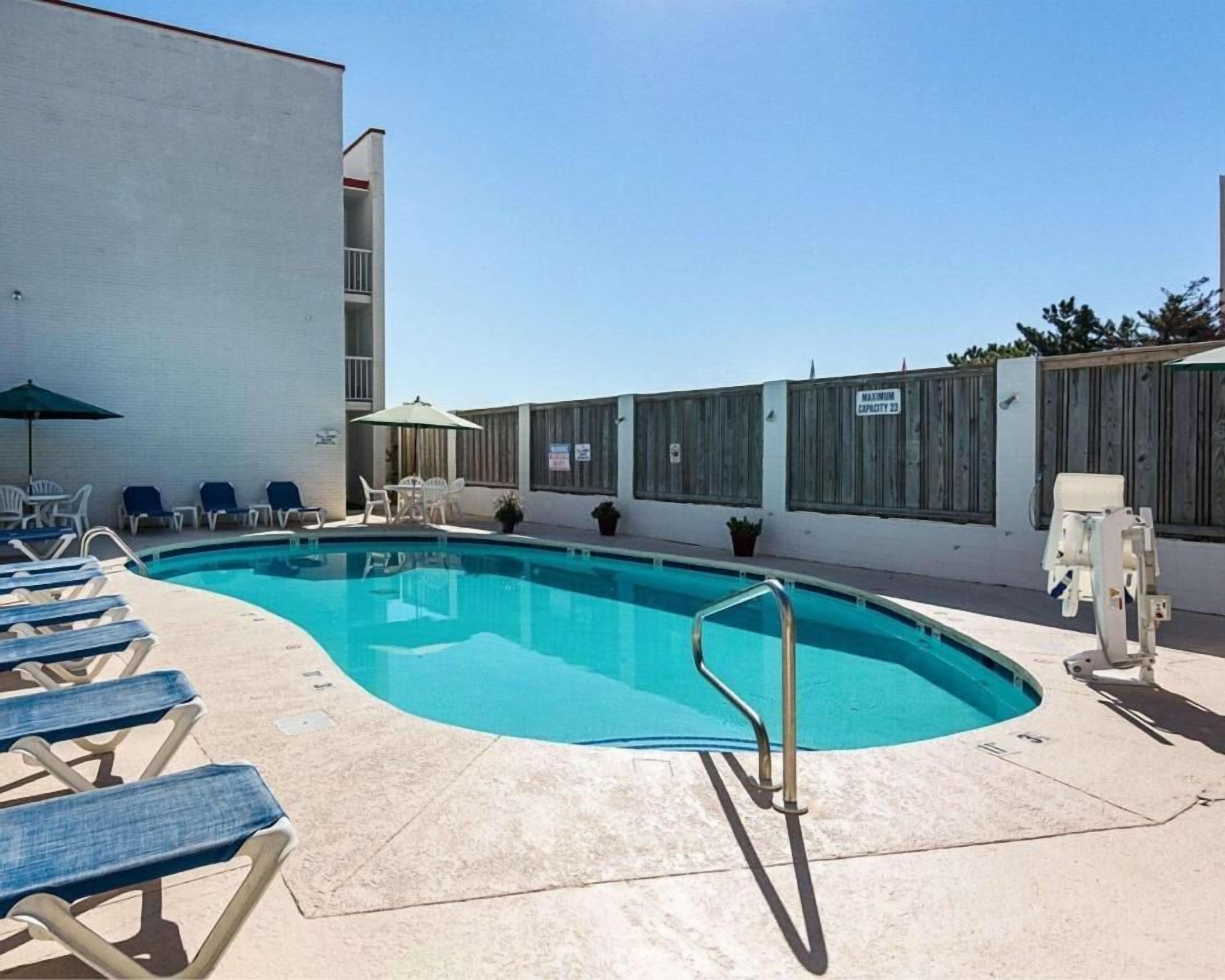 Une piscine avec des chaises longues et un poste de surveillance pour le sauveteur.